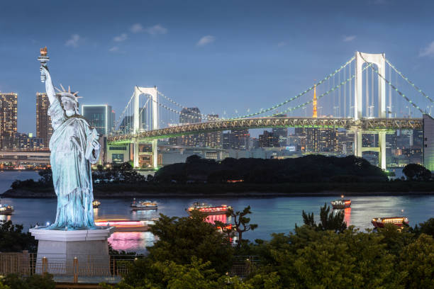 odaiba statue de la liberté avec le rainbow bridge et la tour de tokyo dans la soirée - réplique de la statue de la liberté odaiba photos et images de collection