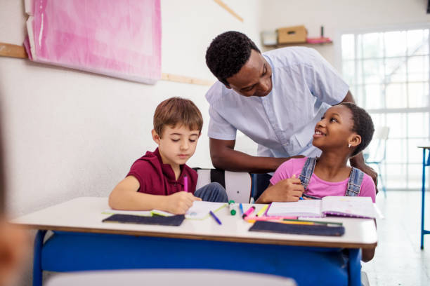 istock Smiling schoolgirl looking at teacher in class 996974750
