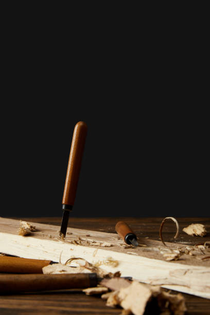 istock sticking chisel in wood at table on black background 996975654