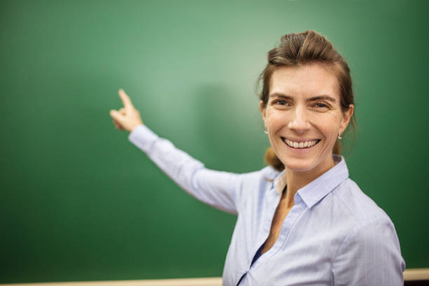 istock Smiling female teacher pointing at blackboard 996989468