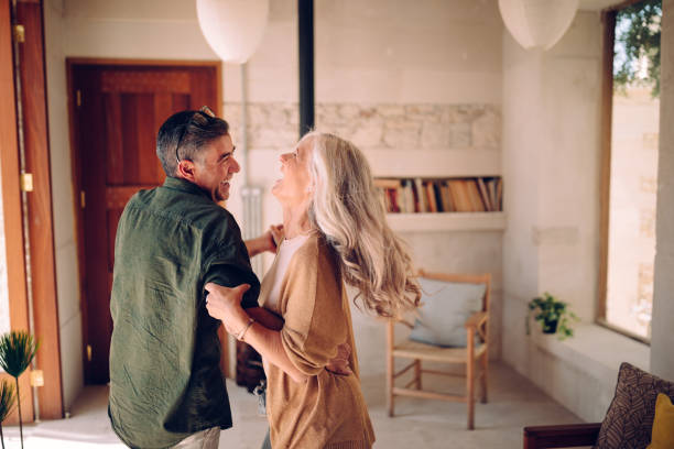 feliz pareja senior bailando y riendo juntos en el hogar - senior adult retirement couple happiness fotografías e imágenes de stock