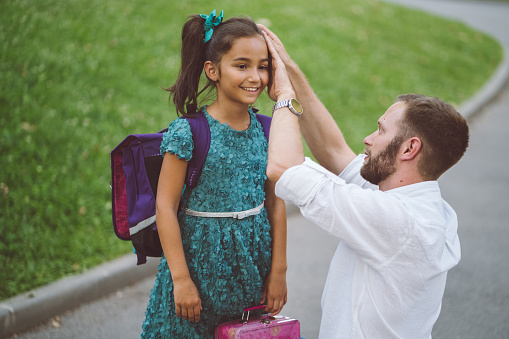 Cute girl saying goodbye to parent and leaving to school