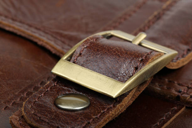 istock Yellow metal clasp on a brown leather surface 996993838