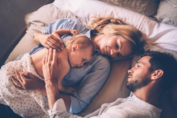 affectionate young parents relaxing in bed with little baby - 2322 imagens e fotografias de stock