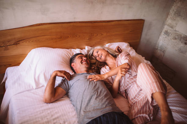 istock Happy mature couple laughing together while lying down in bed 996995174