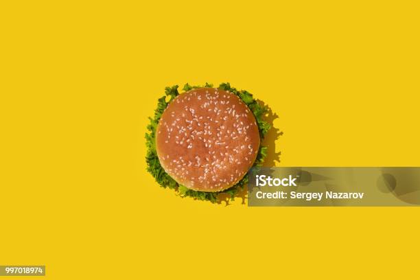 Tasty Fresh Unhealthy Hamburger With Ketchup And Vegetables On Yellow Vibrant Bright Background Top View With Copy Space Stock Photo - Download Image Now