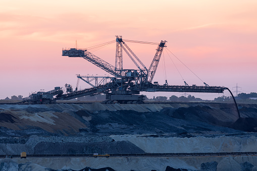 Sunset landscape brown coal open pit with digging machine, Germany