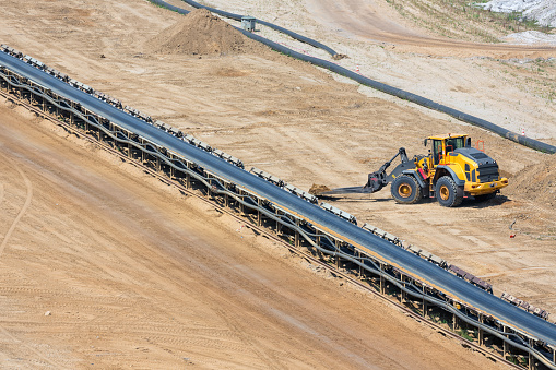 Brown coal open pit landscape with conveyor belt and dozer