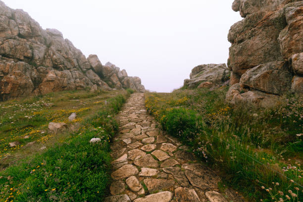Hiking trail between big rocks in foggy weather stock photo