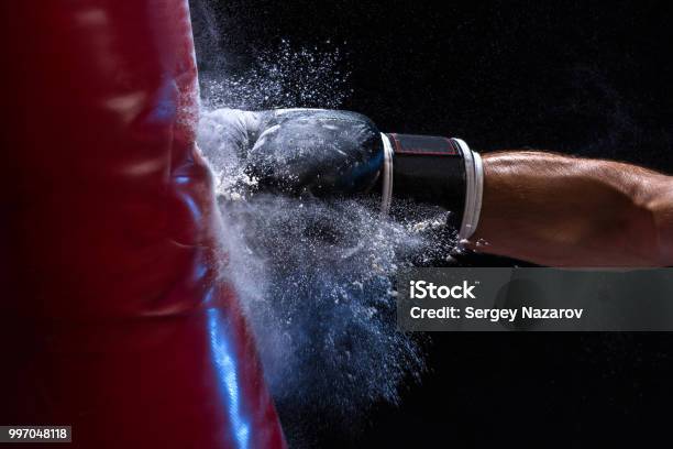 Closeup Hand Of Boxer At The Moment Of Impact On Punching Bag Over Black Background Stock Photo - Download Image Now