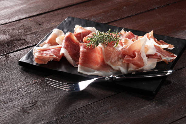 istock Italian prosciutto crudo or jamon with rosemary. Raw ham 997081628