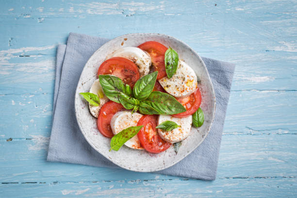 Caprese salad top Caprese salad with mozzarella, basil and tomatoes on blue wooden table. Top view caprese salad stock pictures, royalty-free photos & images