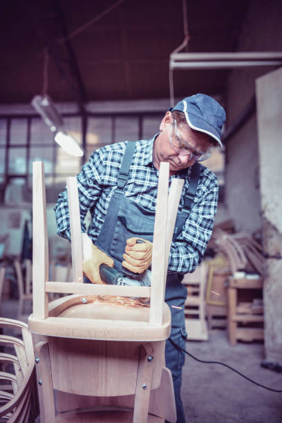istock Senior Carpenter Sawing Chair For Restoration Process 997092362