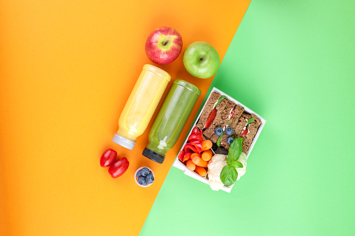 Lunch box with healthy food and juice from fresh berries. Toast and apple. books for school and green background. takeaway food. copy space. flat lay.