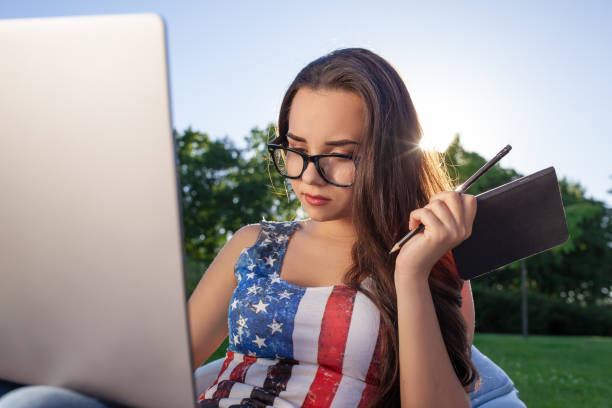 pretty young woman sitting on bean bag use laptop while resting on grass in park on the sun - coffee bean bag human hand imagens e fotografias de stock