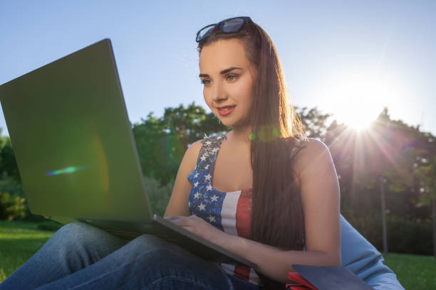 pretty young woman sitting on bean bag use laptop while resting on grass in park on the sun - coffee bean bag human hand imagens e fotografias de stock