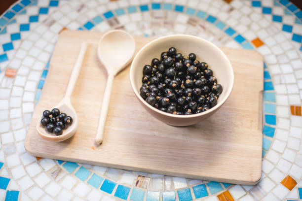 istock A plate of black currant and a wooden spoon on a table. 997105714