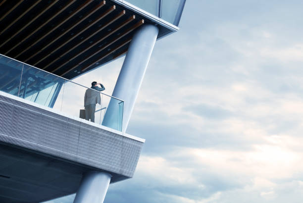 istock Businessman Stands On Balcony Looking Out Into Distance 997107134