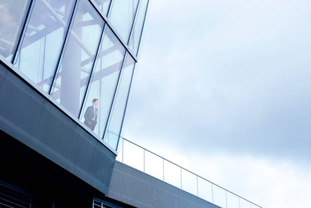istock Businessman Stands Inside Building And Looks Out Through Window 997107322