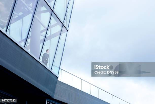 Businessman Stands Inside Building And Looks Out Through Window Stock Photo - Download Image Now