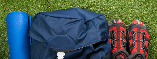 istock tourist shoes, rug and backpack lie on green grass 997111348