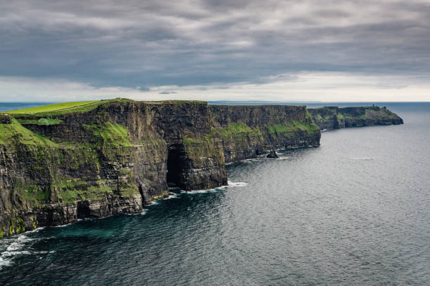 Areal view towards the famous and beautiful Cliffs of Moher under a rainy and dramatic skyscape in summer. Burren Region, County Clare, Ireland