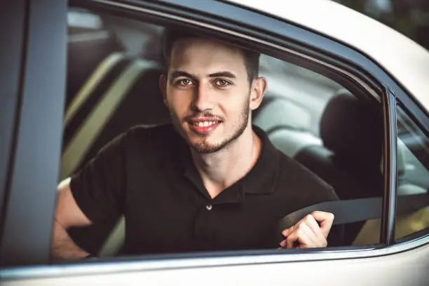 Photo of Passenger man fastening seat belt in the car, safety concept.