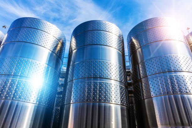 Stainless steel storage tank containers at the chemical plant factory Row of the shiny stainless steel storage tank containers at the chemical plant factory against blue sky with clouds drum container stock pictures, royalty-free photos & images