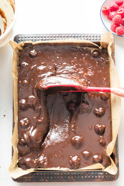 istock Spreading chocolate brownies batter cake with raspberries on baking tray 997132564