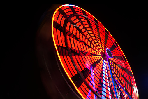 Motion blur of a colorful ferris wheel at night showing a flower pattern.