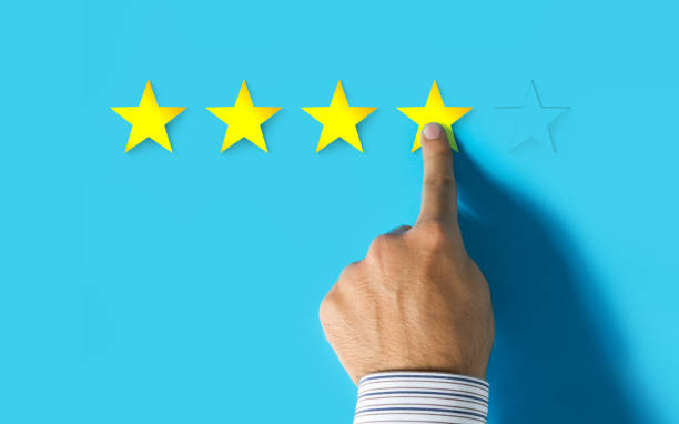 istock Hand choosing 4 yellow stars on blue background - Good feedback concept 997178556