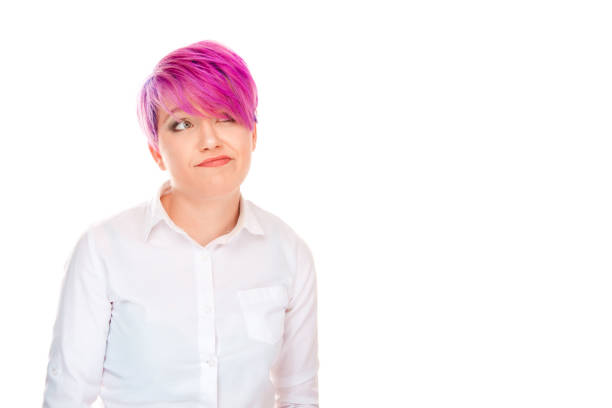 Portrait of a stylish and trendy woman wearing a denim jacket and beanie, presenting two rubber duck toys, over a vivid yellow background.