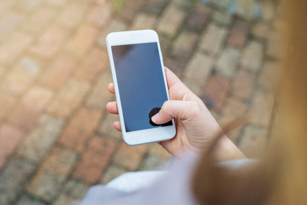 Gros plan d’une main féminine en utilisant un téléphone portable / smartphone à l’extérieur - Photo