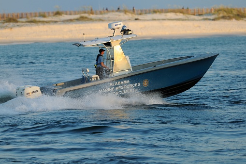 Orange Beach, Alabama, USA - June 19, 2011: Alabama Marine Resources Enforcement power boat driven by ranger speeding along coast.