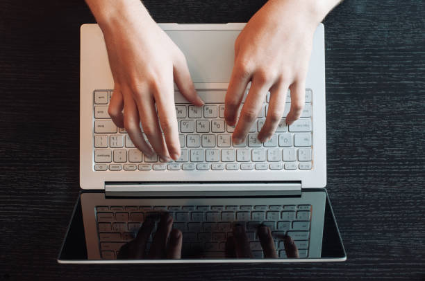 Top view of human hands typing on laptop keyboard