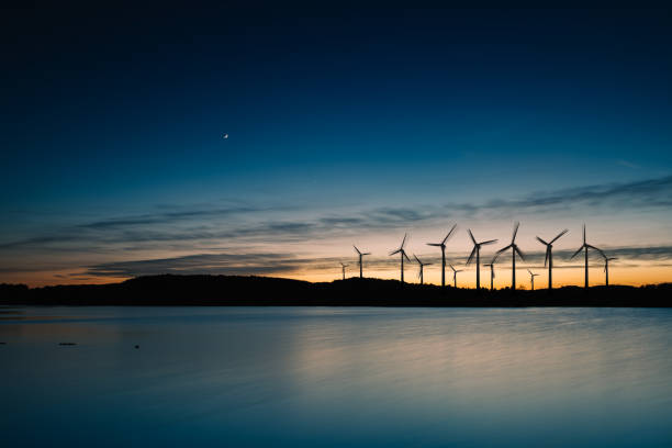 tramonto sul paesaggio del movimento delle turbine eoliche - green sky water wave foto e immagini stock