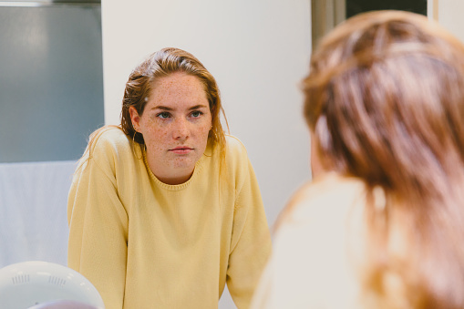 Depressed Teen Looks At Herself in Bathroom Mirror