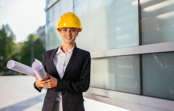 istock Female architect with yellow helmet and blueprints 997290200