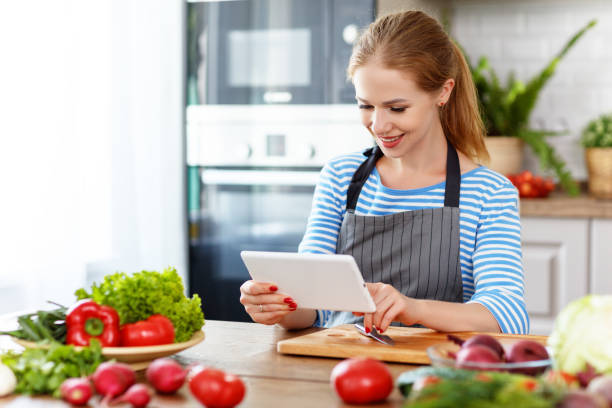 istock happy woman preparing vegetables in kitchen on prescription with tablet 997290580