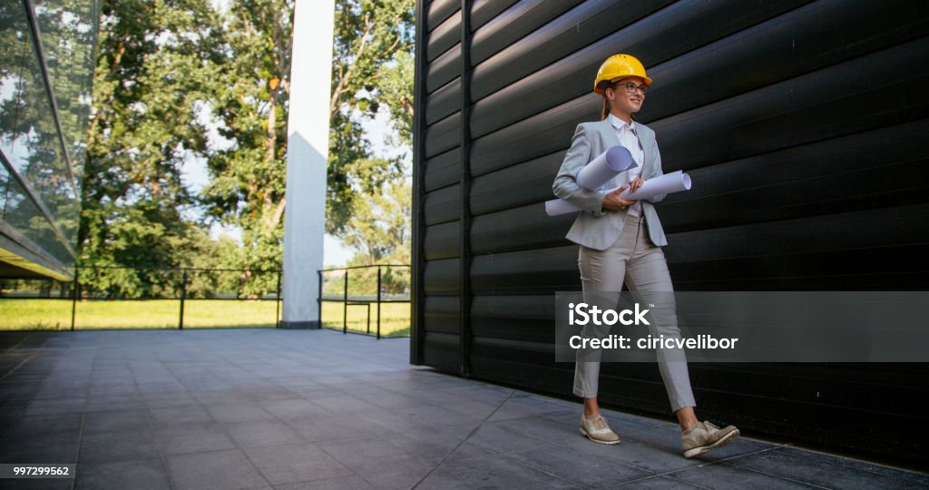 Female architecte with yellow helmet and blueprints Young pretty woman holding blue prints Adult Stock Photo