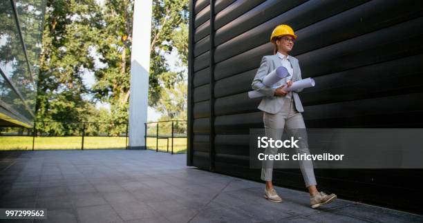 Female Architecte With Yellow Helmet And Blueprints Stock Photo - Download Image Now