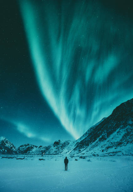 istock Young man watching Aurora Borealis in winter, Lofoten, Norway 997324498