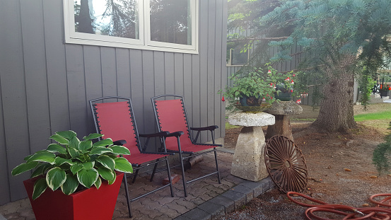 Small patio with plants in pots and garden antiques. Surrounded by Spruce trees.