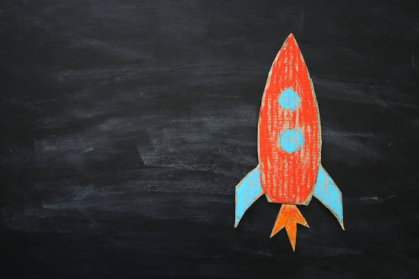 istock Rocket cut from cardboard and painted over chalkboard background. 997341564
