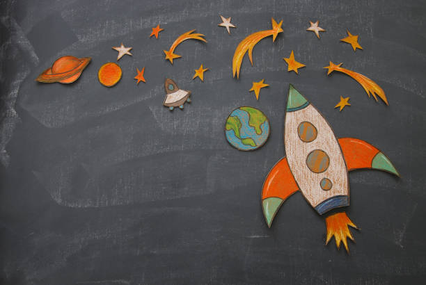 istock Rocket cut from paper and painted over class room blackboard background. 997341722