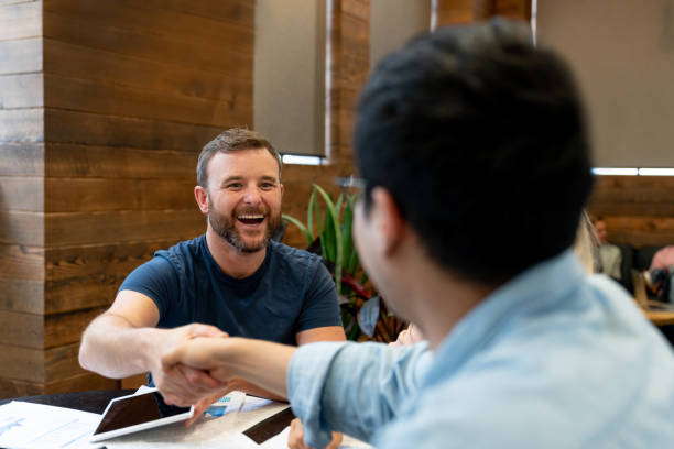 Men handshaking at the office closing a deal Portrait of two happy men handshaking in a meeting at the office and closing a deal casual handshake stock pictures, royalty-free photos & images