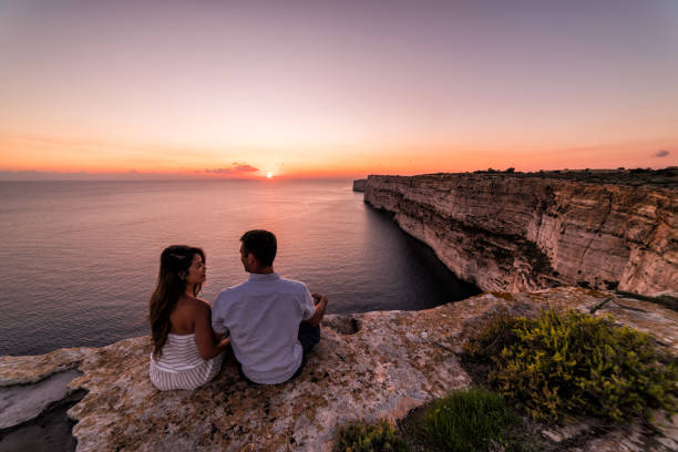 Couple overlooks the Ta Cenc cliffs at sunset.  Gozo, Malta