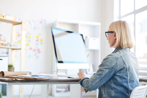 istock Serious confident busy woman in denim jacket working on graphic design and using computer in modern office 997397648