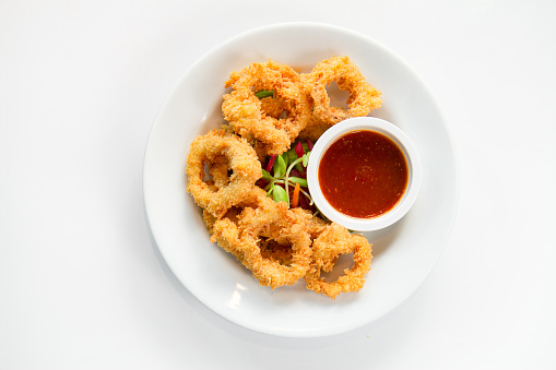 Fried crispy squid rings breaded ( caramari ) with red sauce on white backgruond