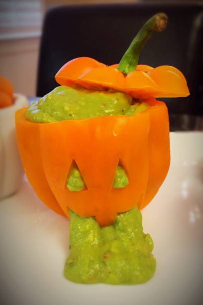 Guacamole "Pumpkin" An orange bell pepper is sliced like a jack-o-lantern, and is filled with guacamole to create a Halloween-effect appetizer. pumpkin throwing up stock pictures, royalty-free photos & images